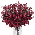 Burgundy artificial baby's breath flowers in a clear glass vase, close-up view