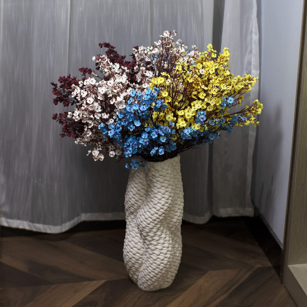 Bouquet of artificial baby's breath flowers in burgundy, white, blue, and yellow in a textured white vase.