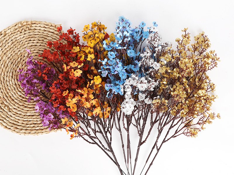 Bundle of artificial baby's breath flowers in various colors arranged on a white background with a woven mat.