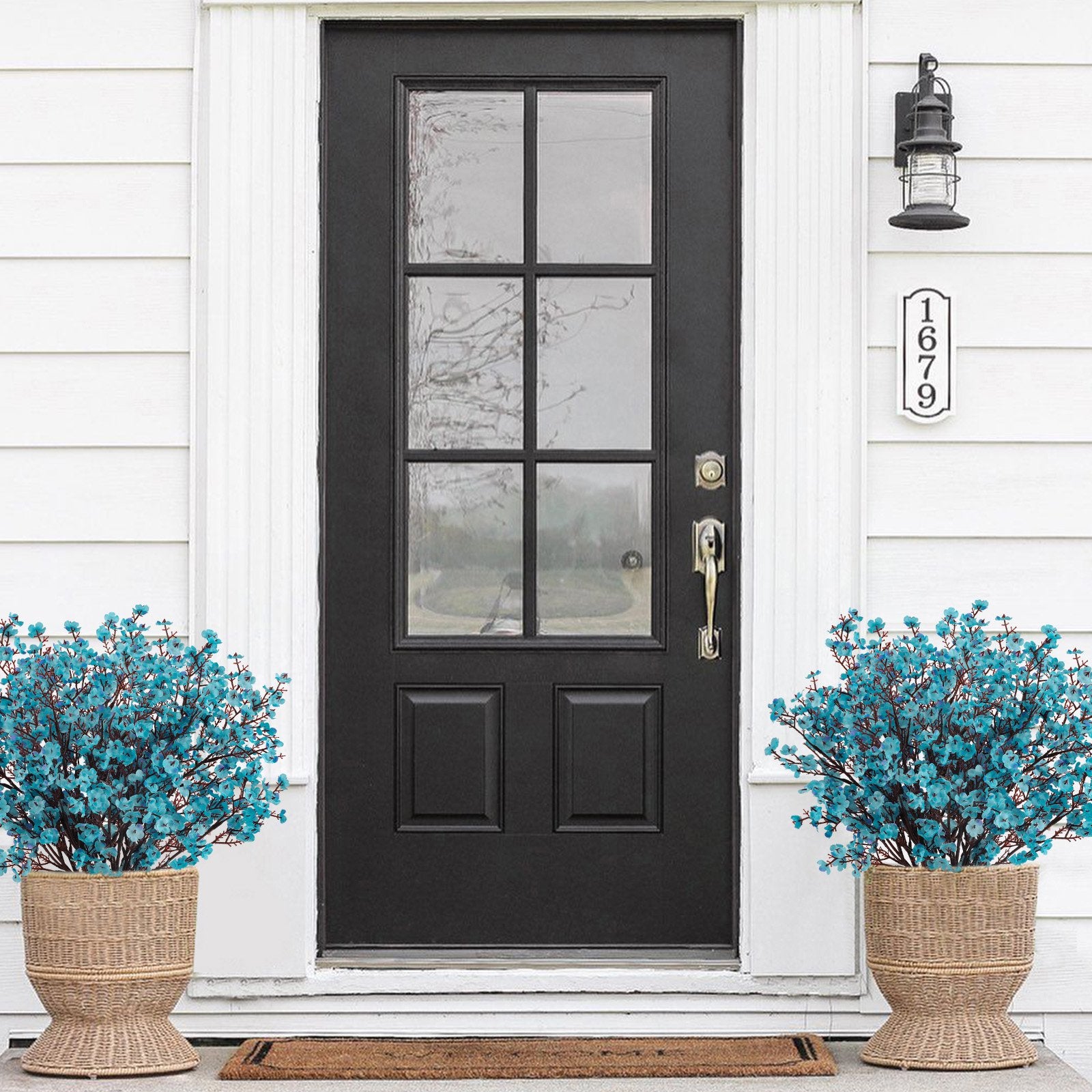 Two bundles of artificial blue baby's breath flowers in woven baskets flanking a black front door.
