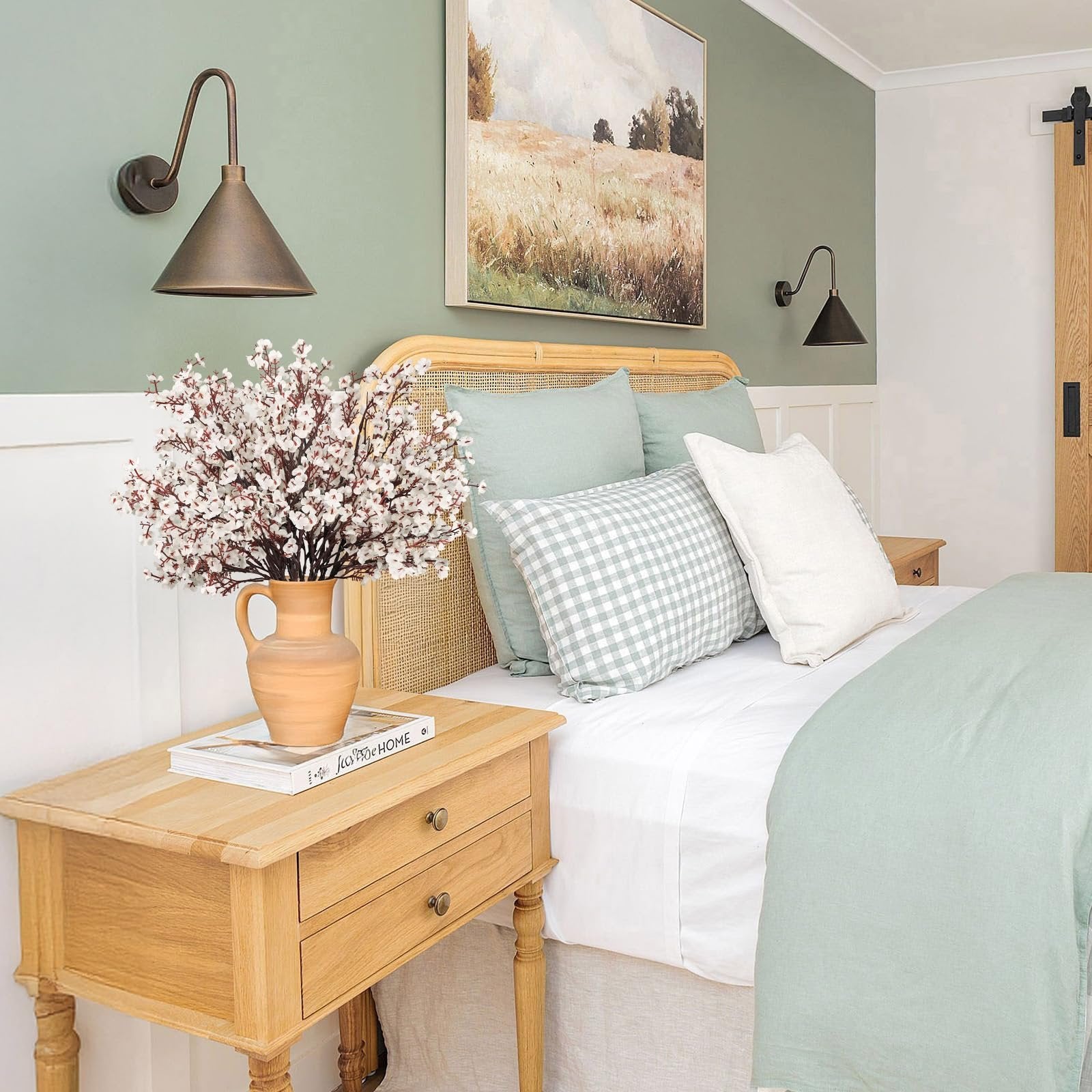 White baby's breath flowers in a terracotta vase on a wooden nightstand next to a bed.
