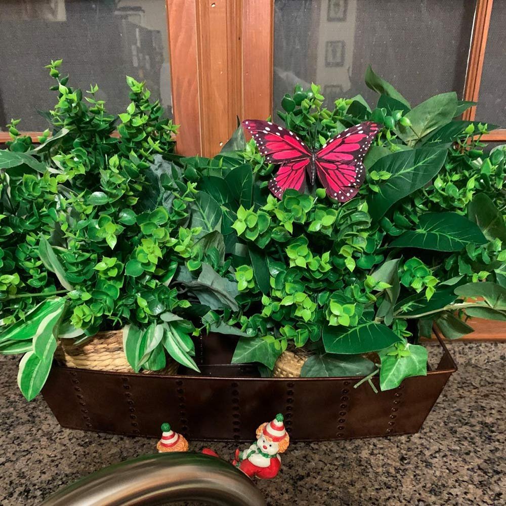 Artificial boxwood stems in a decorative planter with a red butterfly and two small gnome figures