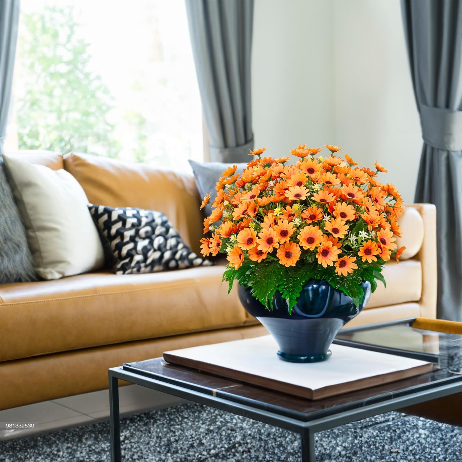 Artificial orange sunflowers in a dark blue vase on a coffee table in a living room setting.