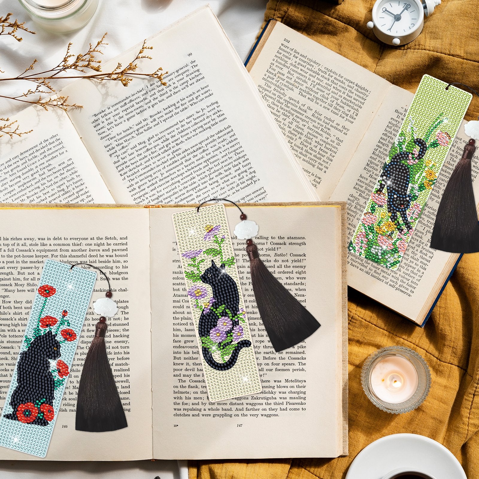 Diamond art cross bookmarks with black cats and flowers, laid on open books with tassels.