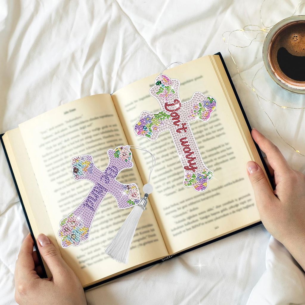 Two diamond art cross bookmarks with tassels resting on an open book, one with 'Don't worry' text.