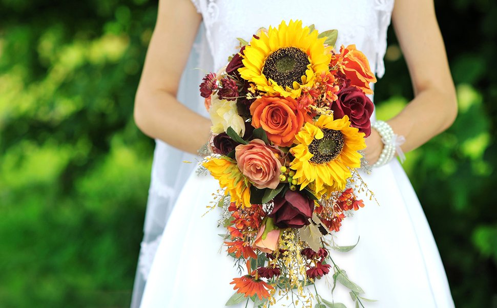 Bride holding a cascading bouquet of sunflowers, roses, and other fall-colored flowers.