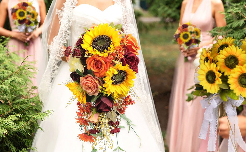 Bride holding a cascading bouquet of sunflowers, roses, and other flowers, with bridesmaids holding bouquets in the background.