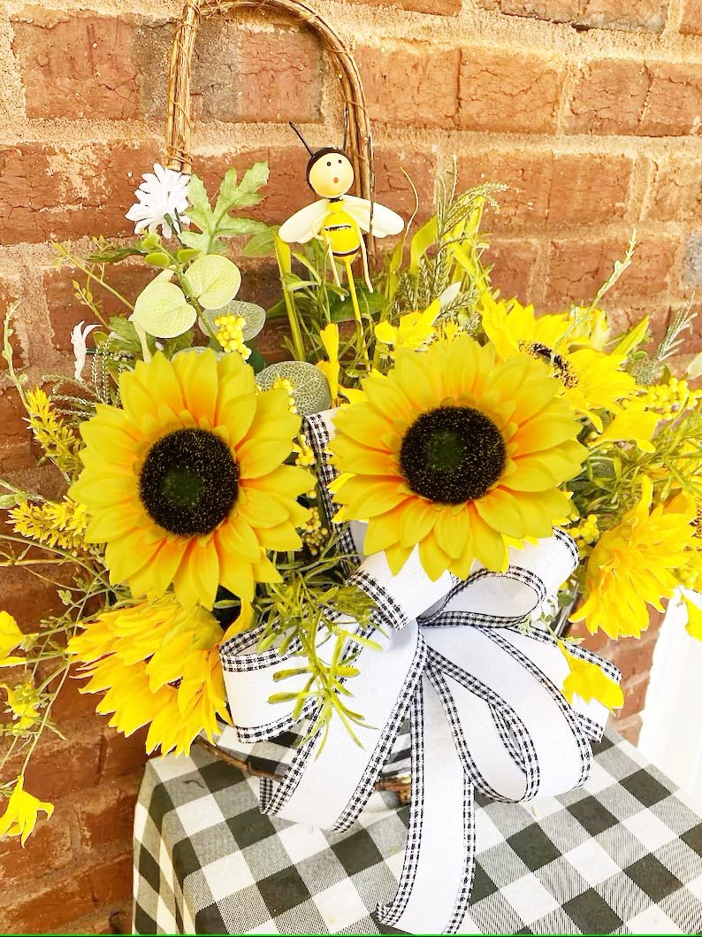 Artificial sunflower arrangement with a bee decoration and a gingham bow, displayed against a brick wall.