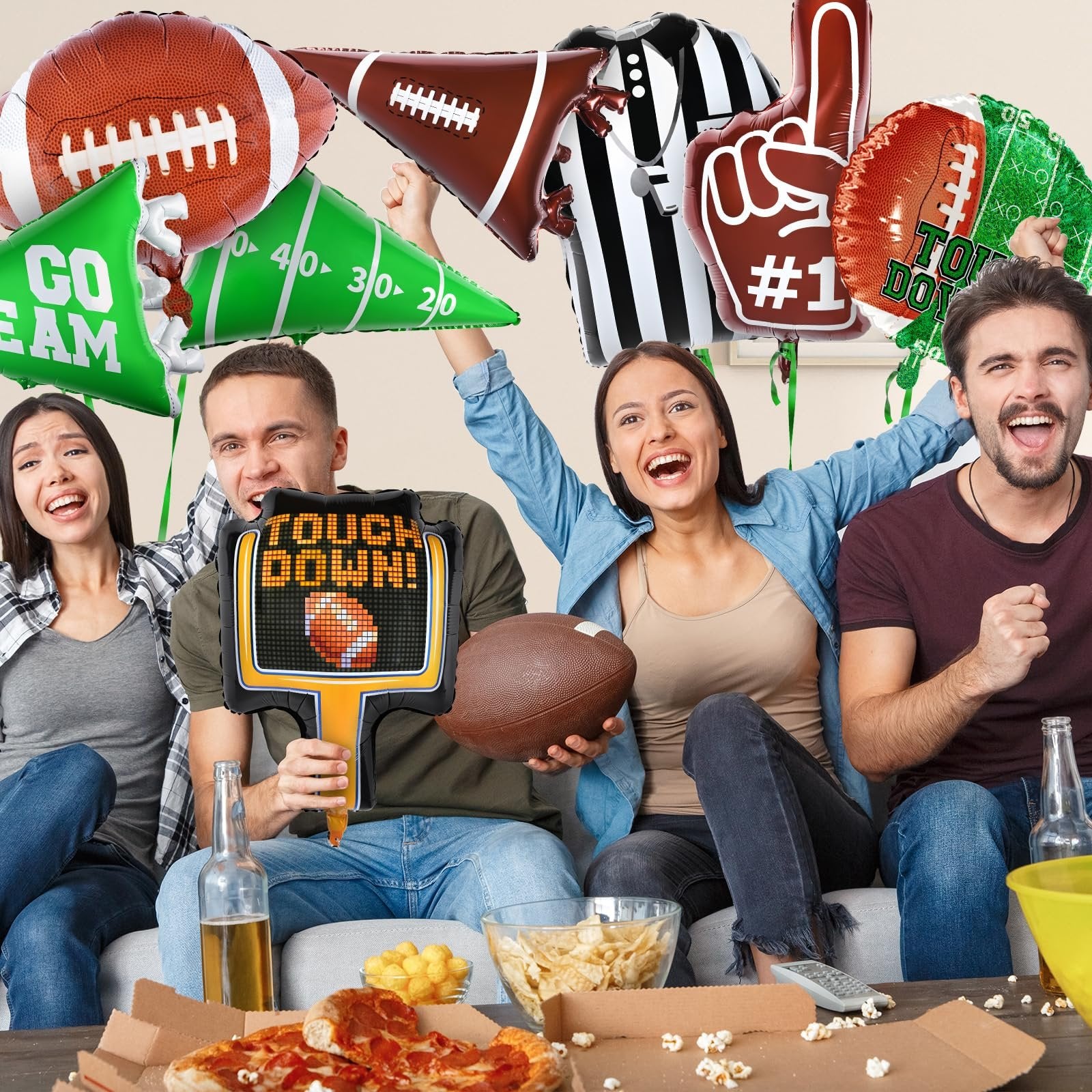 Four people celebrating with football-themed balloons and snacks, holding a touchdown sign.