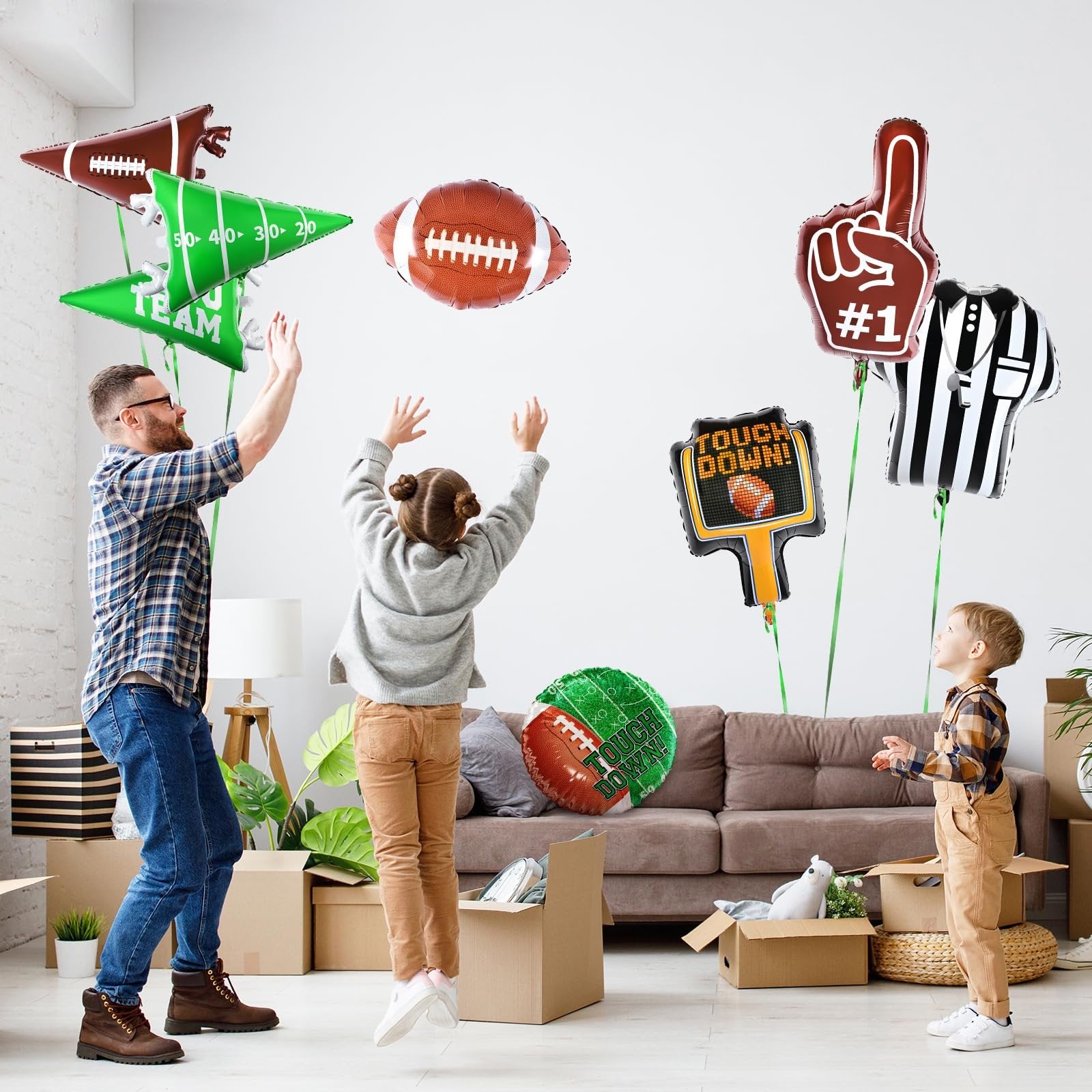 Family playing with football-themed balloons indoors, with moving boxes and furniture visible.