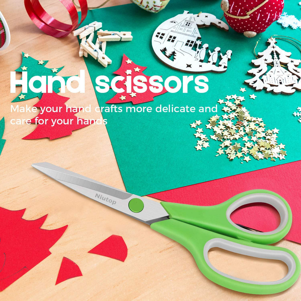 Green handled scissors with branding on the blade, surrounded by craft supplies like paper cutouts and wooden ornaments.