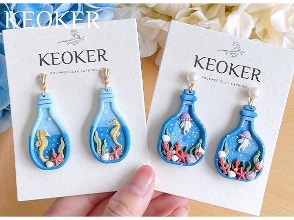 Pair of blue bottle-shaped polymer clay earrings with seahorses and jellyfish, displayed on white cards.