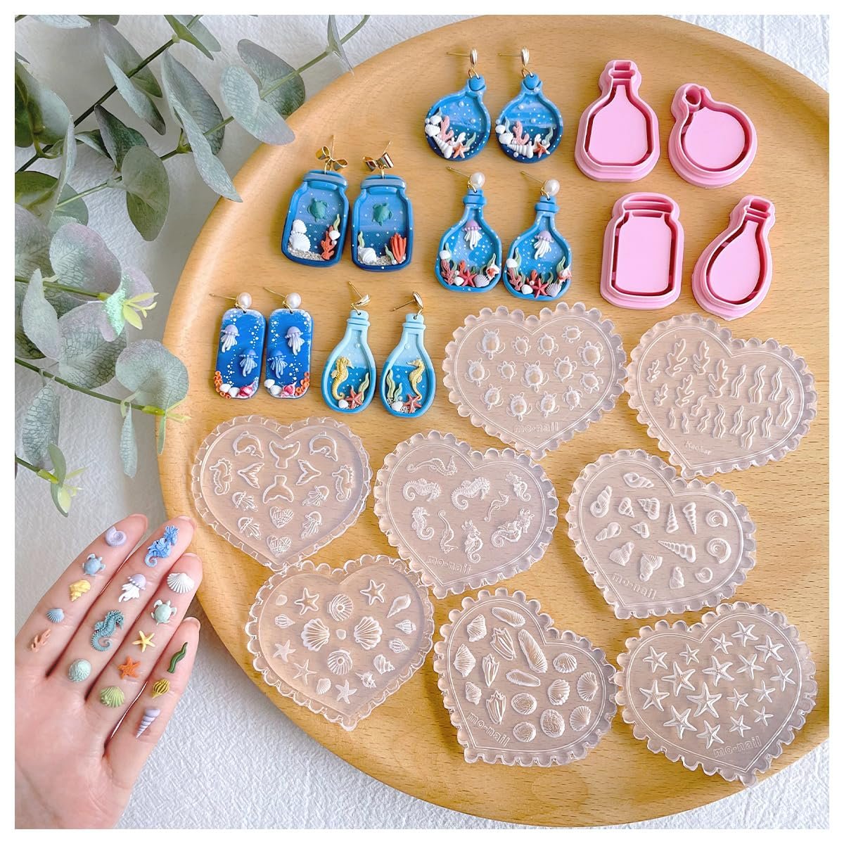 Ocean-themed silicone molds and clay cutters for jewelry making, arranged on a wooden tray.