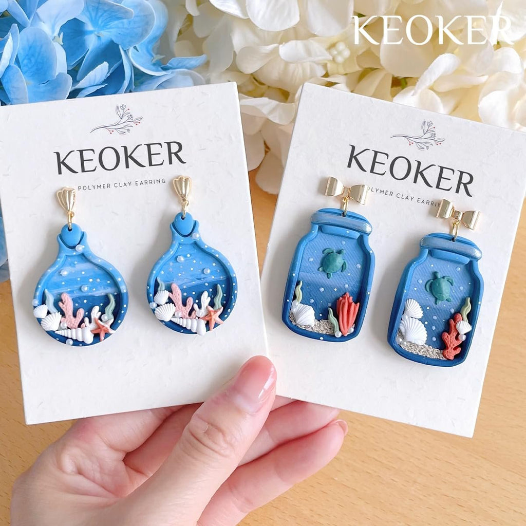 Two pairs of blue ocean-themed polymer clay dangle earrings, one pair shaped like bottles, the other like jars, displayed on white cards.