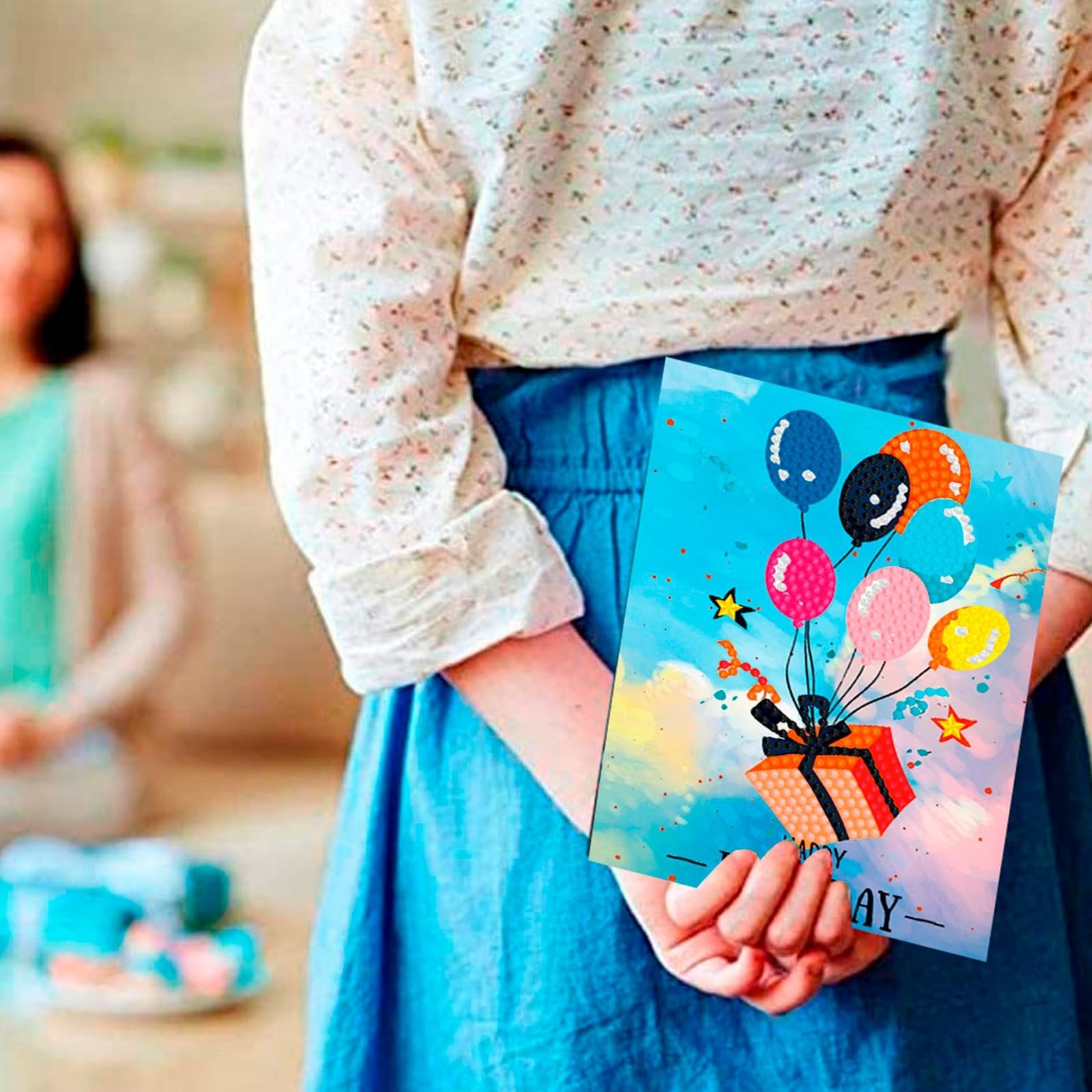 Diamond art birthday card with balloons and gift box design, held by a person.