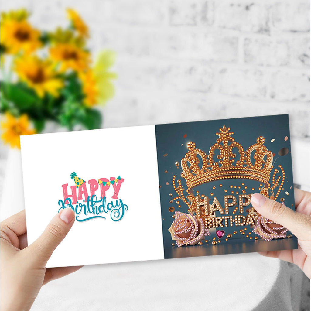 Hands holding open a diamond painting greeting card kit with a crown design and 'Happy Birthday' text.