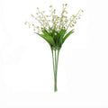 Bunch of artificial white lily of the valley flowers with green leaves and stems tied with twine