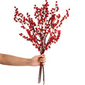 Hand holding artificial red berry stems with white background