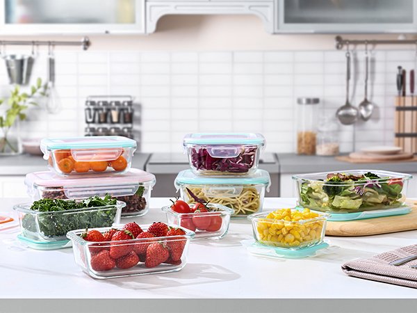 Assortment of glass food storage containers filled with various foods, arranged on a kitchen counter.