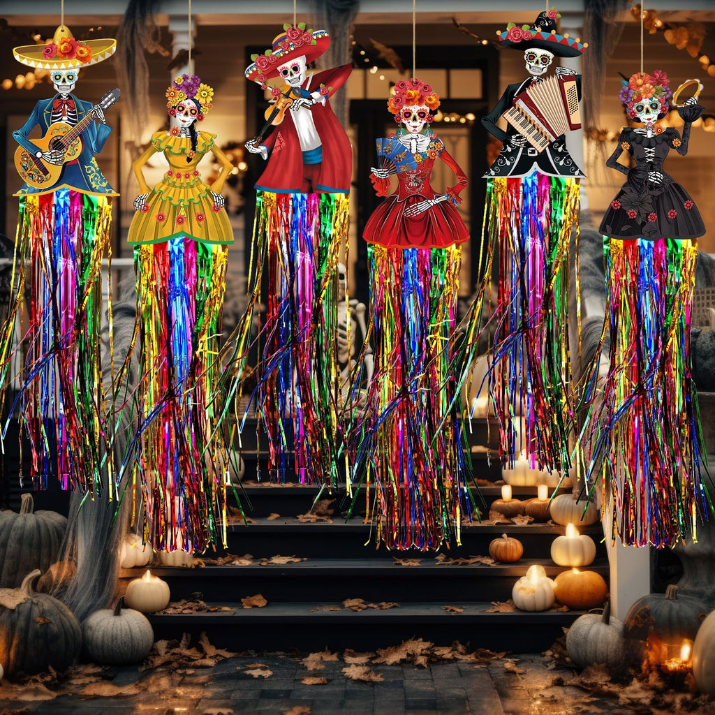 Day of the Dead sugar skull hanging decorations with colorful fringe, displayed on a porch with pumpkins and fall leaves.