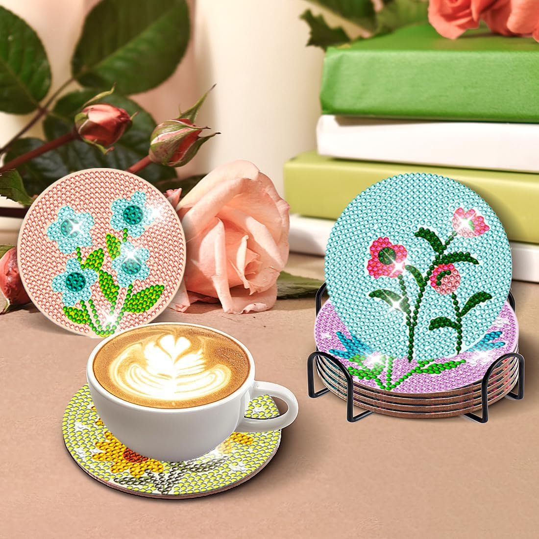 Diamond art coasters with flower designs in a holder next to a coffee cup and roses