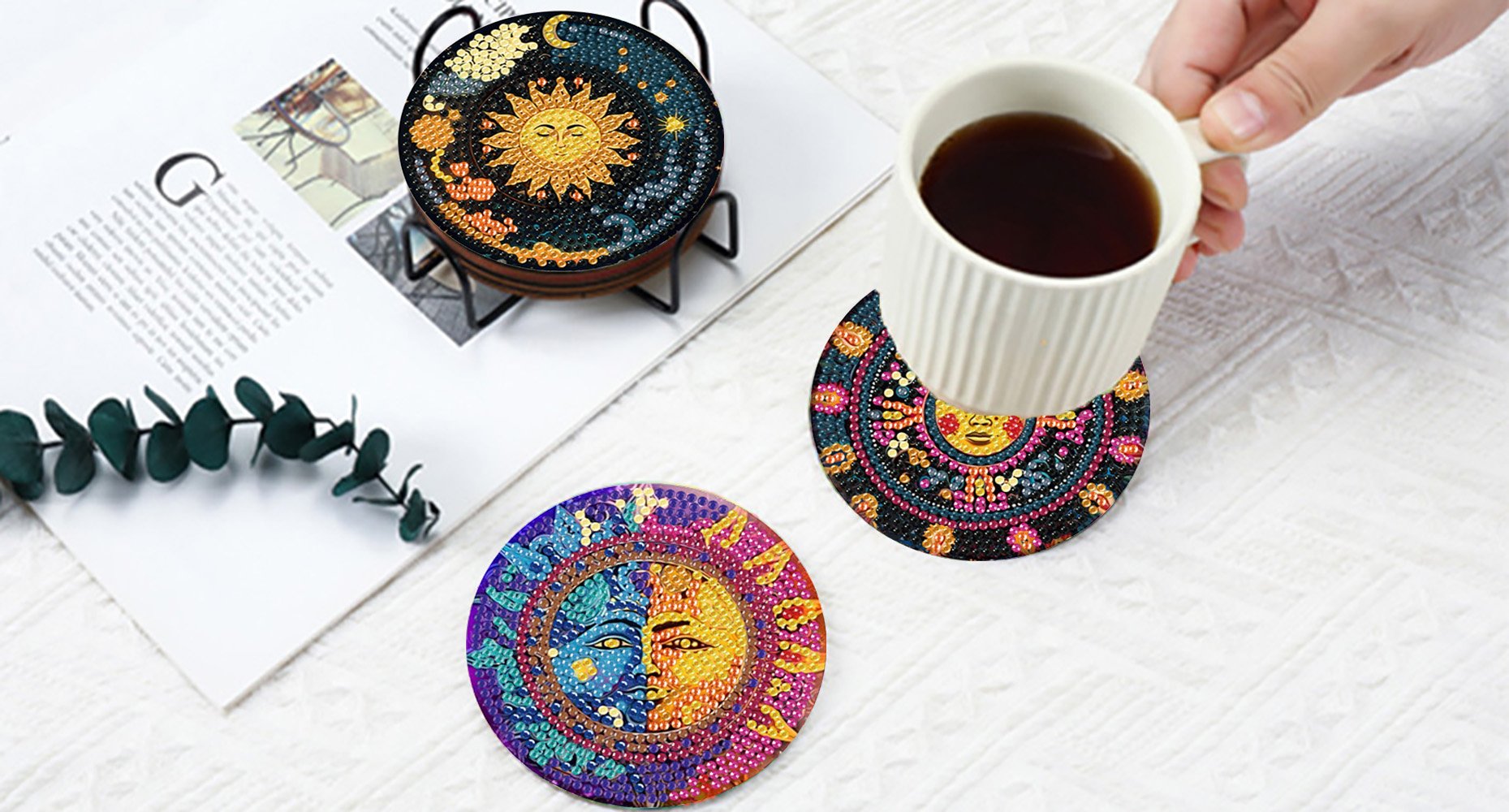 Diamond art coasters with sun and moon designs displayed on a table with a cup of coffee.