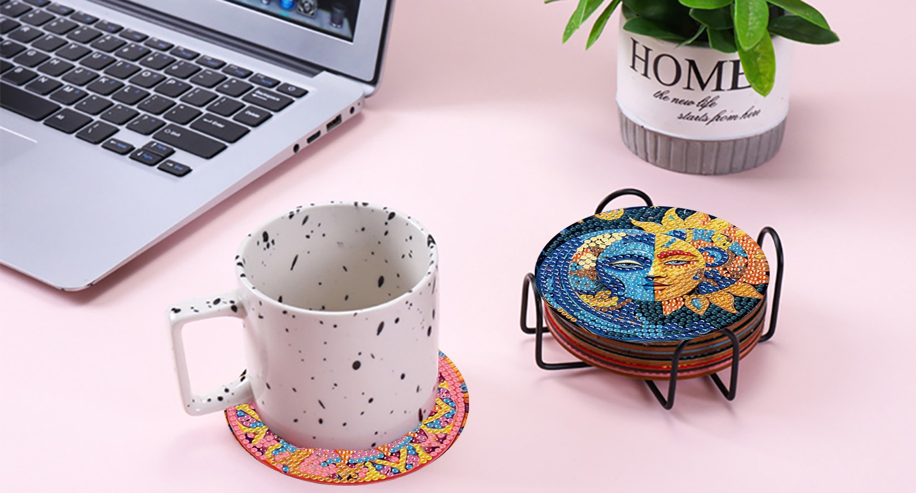 Diamond art coasters with sun and moon designs in a holder next to a mug and laptop