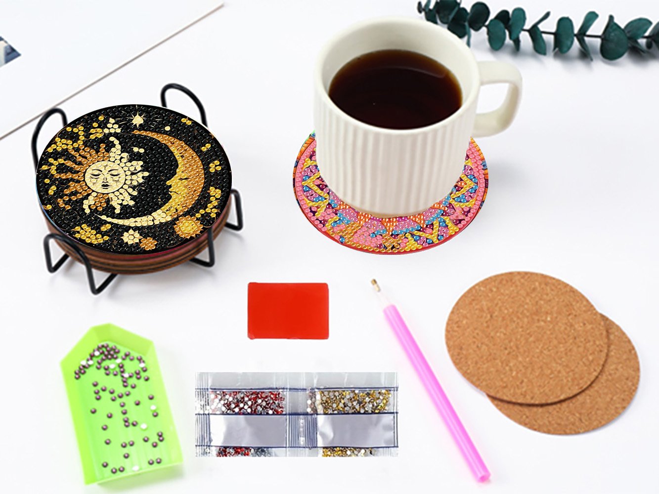 Diamond art coaster kit with sun and moon design, cup, diamond tray, tool, and cork pads on a white surface.