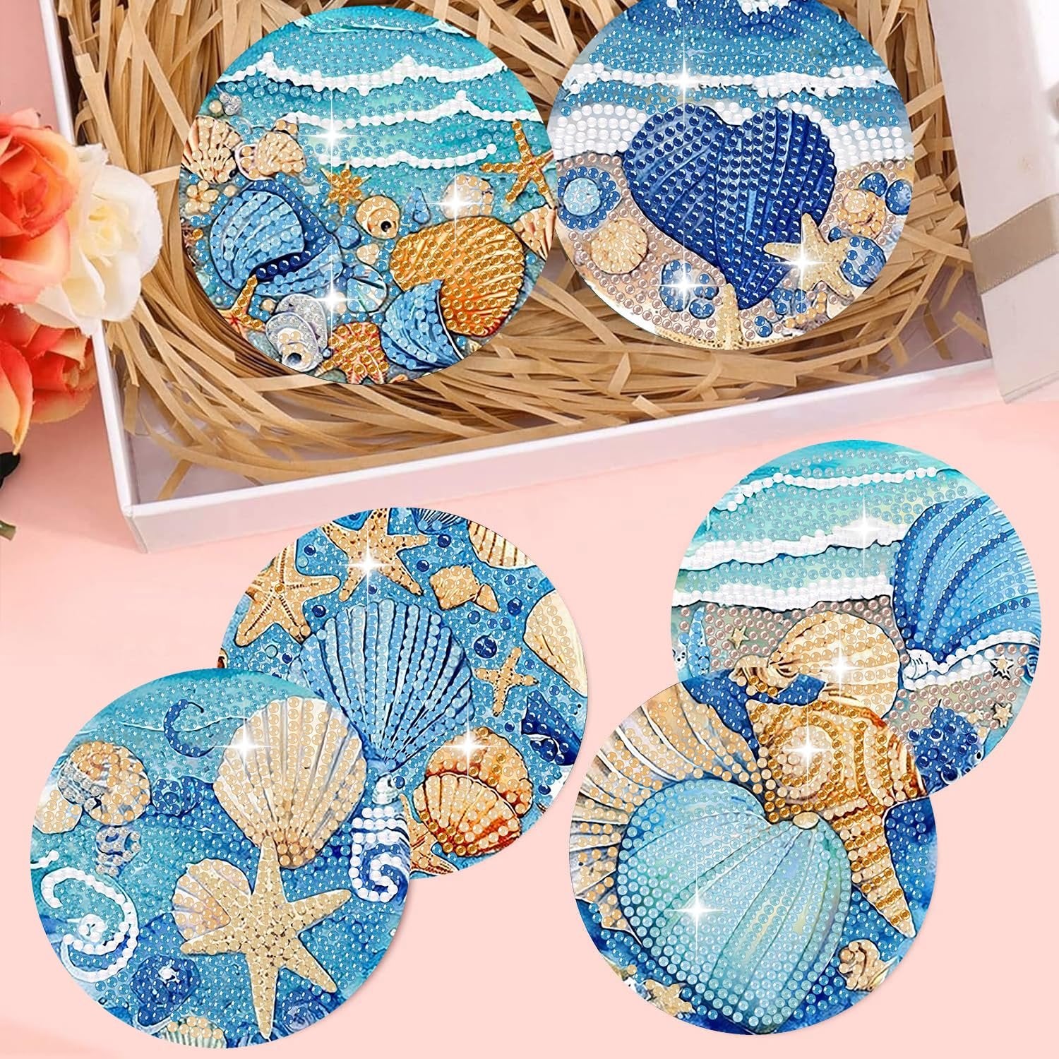 Diamond art coasters with ocean animal designs, including shells and starfish, displayed in a box with decorative flowers.