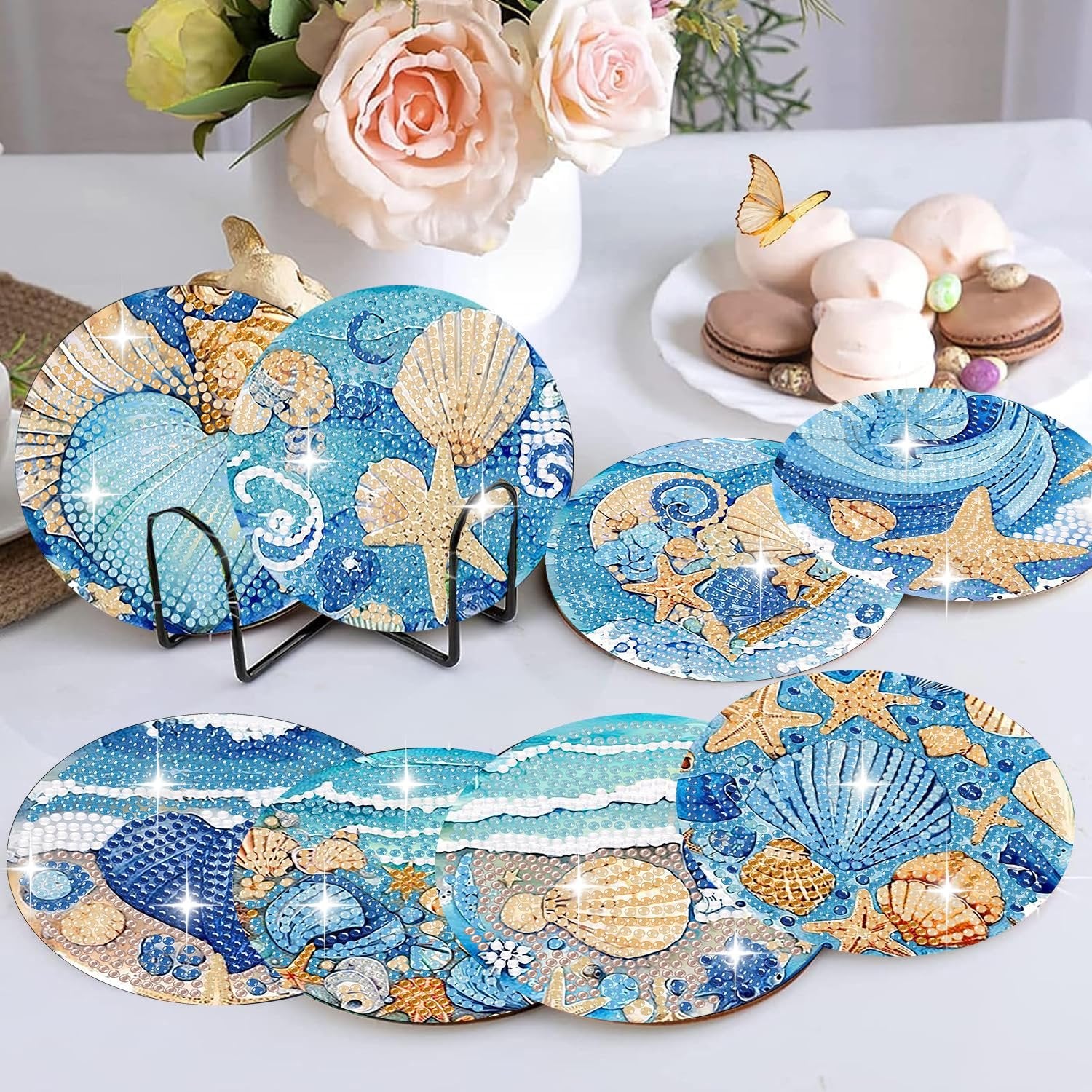 Diamond art coasters with ocean animal designs displayed on a table with flowers and macarons