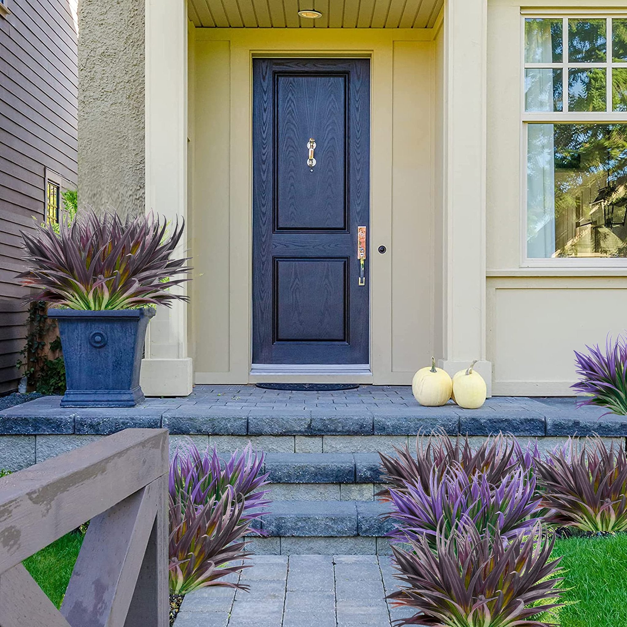 Artificial purple grass plants flanking a front door with pumpkins on the steps