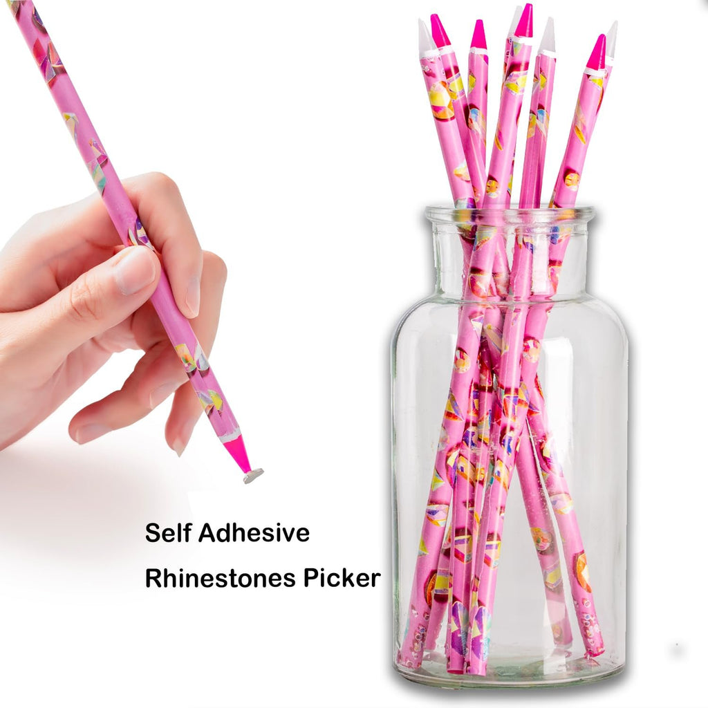 Hand holding a pink patterned rhinestone picker tool with a wax tip, next to a glass jar filled with similar tools.
