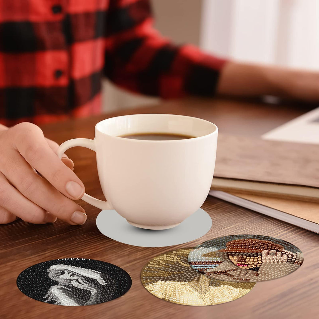 Diamond art coasters with singer designs on a wooden table with a coffee cup
