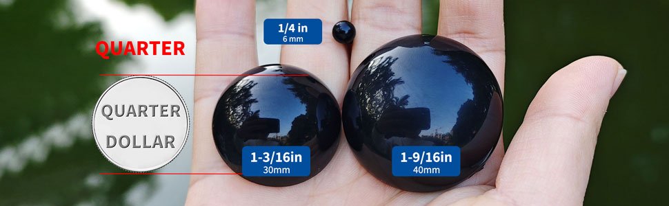 Hand holding two large black plastic safety eyes, one 30mm and one 40mm, with a 6mm eye for scale, next to a quarter dollar coin.