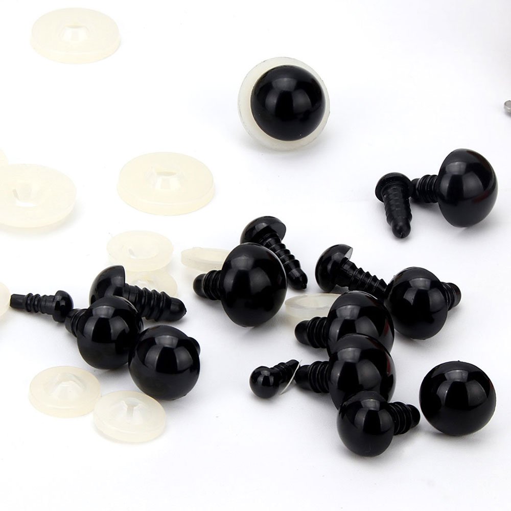 Black plastic safety eyes with clear washers scattered on a white background, close-up view.