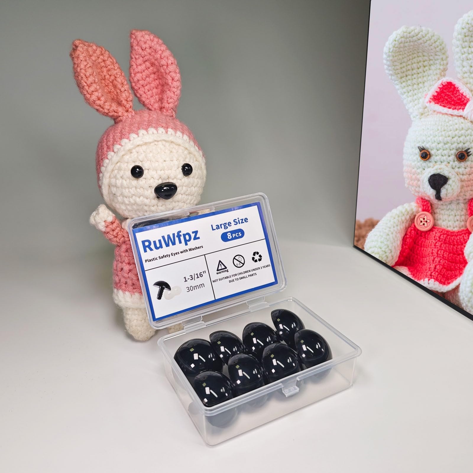 Black plastic safety eyes with washers in a clear case next to a crocheted bunny toy.