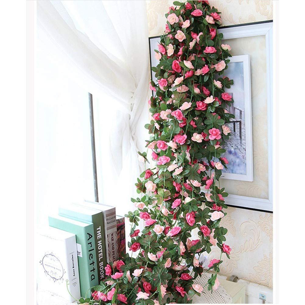 Pink and red artificial rose flower garlands draped next to a window with books and a framed picture.