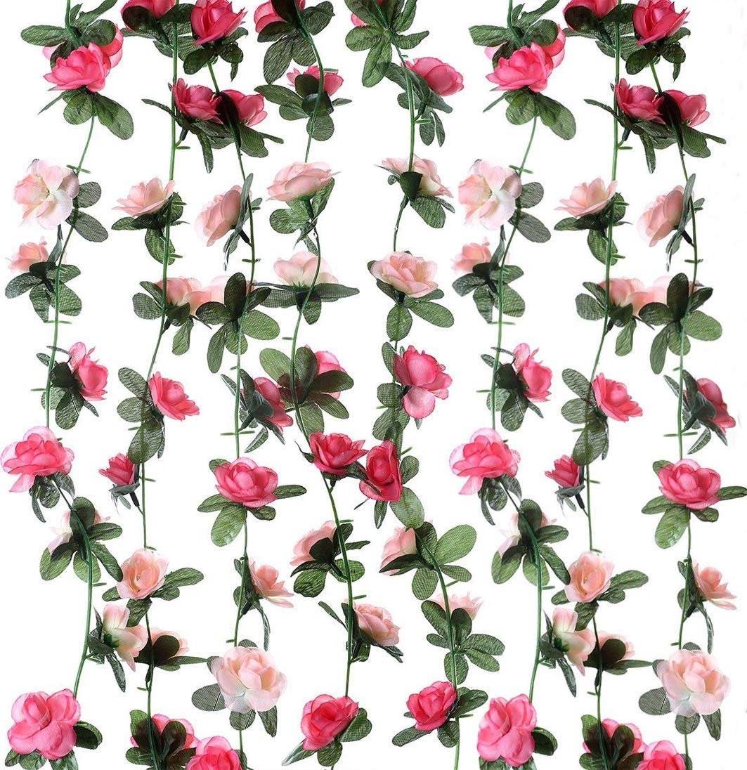 Multiple strands of artificial pink and red roses with green leaves against a white background.