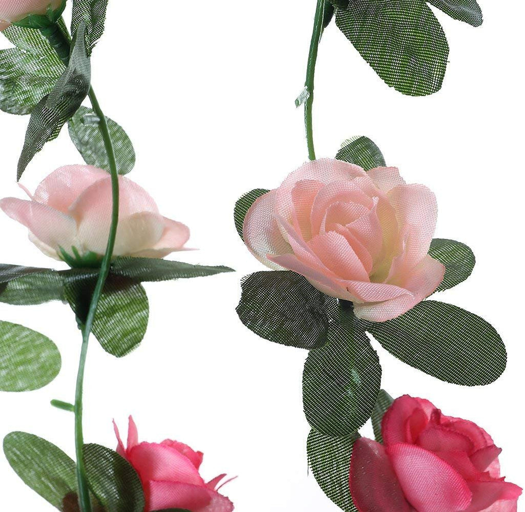 Close-up of artificial pink and red rose flower garlands with green leaves against a white background.