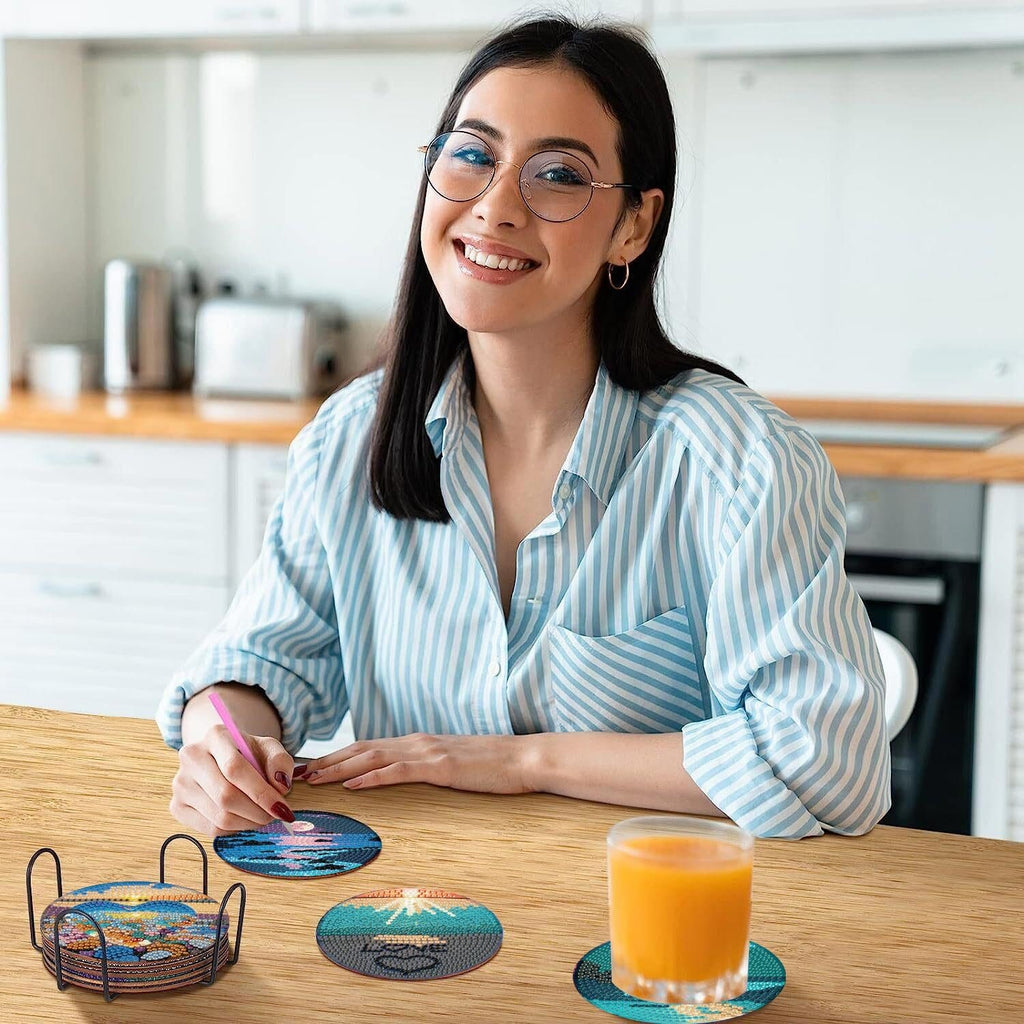 Woman smiling at table with diamond art coasters and holder, glass of orange juice