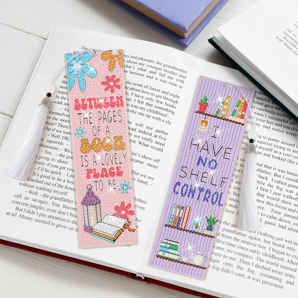 Diamond art bookmarks with tassels, one reads 'Between the Pages of a Book is a Lovely Place to Be', the other reads 'I Have No Shelf Control'.