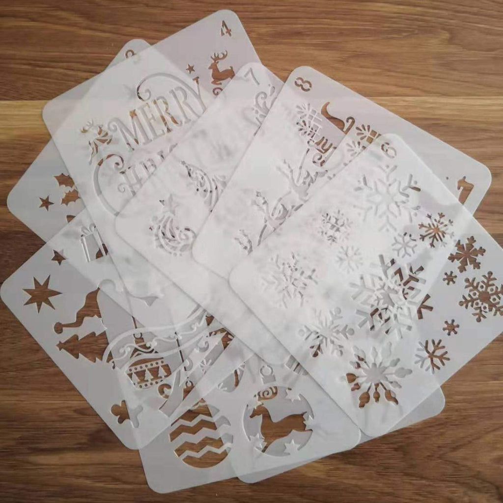 Set of 8 white plastic Christmas stencils with holiday designs like snowflakes, reindeer, and trees, fanned out on a wooden surface.