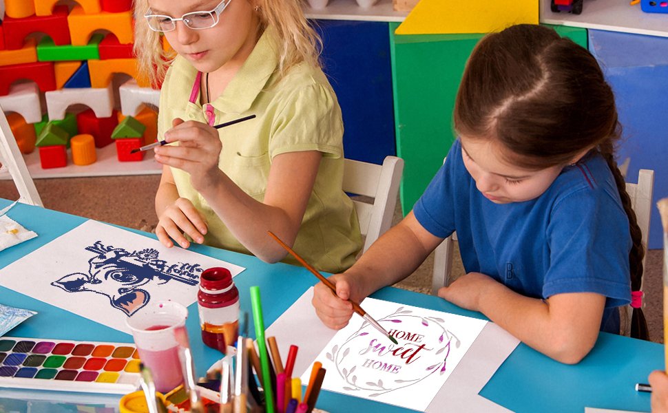 Two girls painting farm animal and home sweet home designs on paper at a table with art supplies