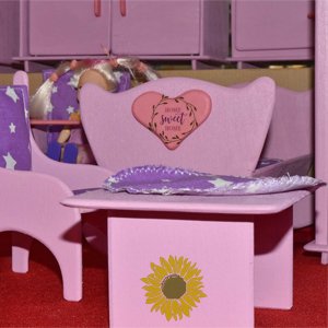 Pink dollhouse furniture with a heart decal that says 'Home Sweet Home' and a sunflower decal on a table.