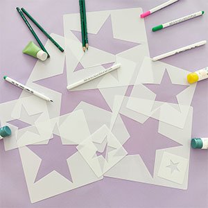 Eight large star stencils in various sizes, with pencils, markers, and paint tubes arranged around them on a light purple surface.