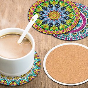 Diamond painting mandala coasters with cork bases next to a cup of coffee on a wooden table
