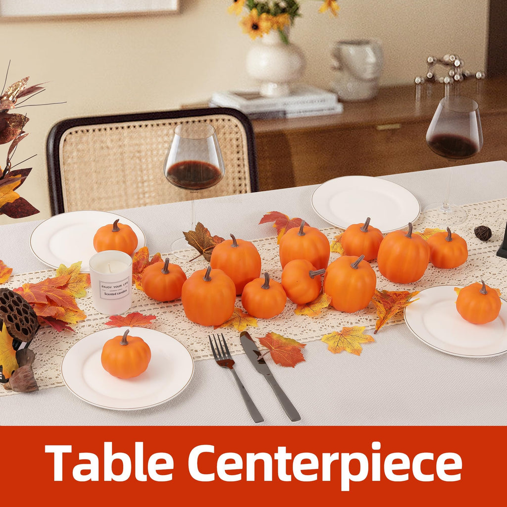 Table setting with artificial pumpkins and fall leaves, featuring plates, wine glasses, and a candle.