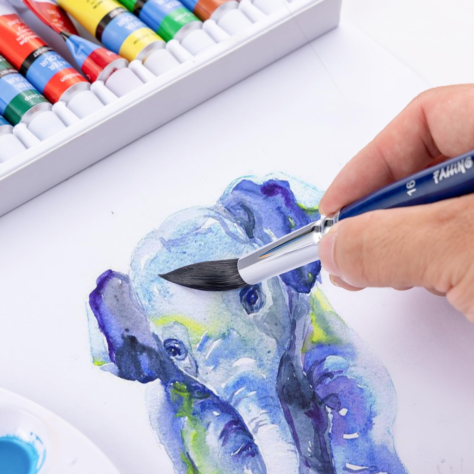Hand holding a blue paintbrush with '' logo and '16' on the handle, painting a watercolor elephant.