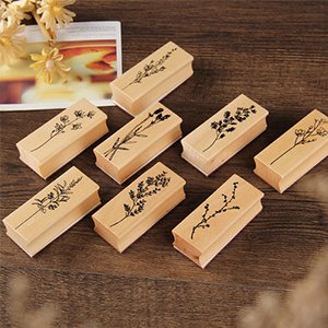 Eight wood-mounted rubber stamps with botanical floral and plant patterns, arranged on a wooden surface.