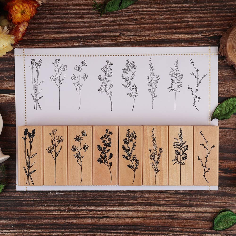 Eight wood-mounted rubber stamps with botanical floral and plant designs, displayed on a wooden surface.